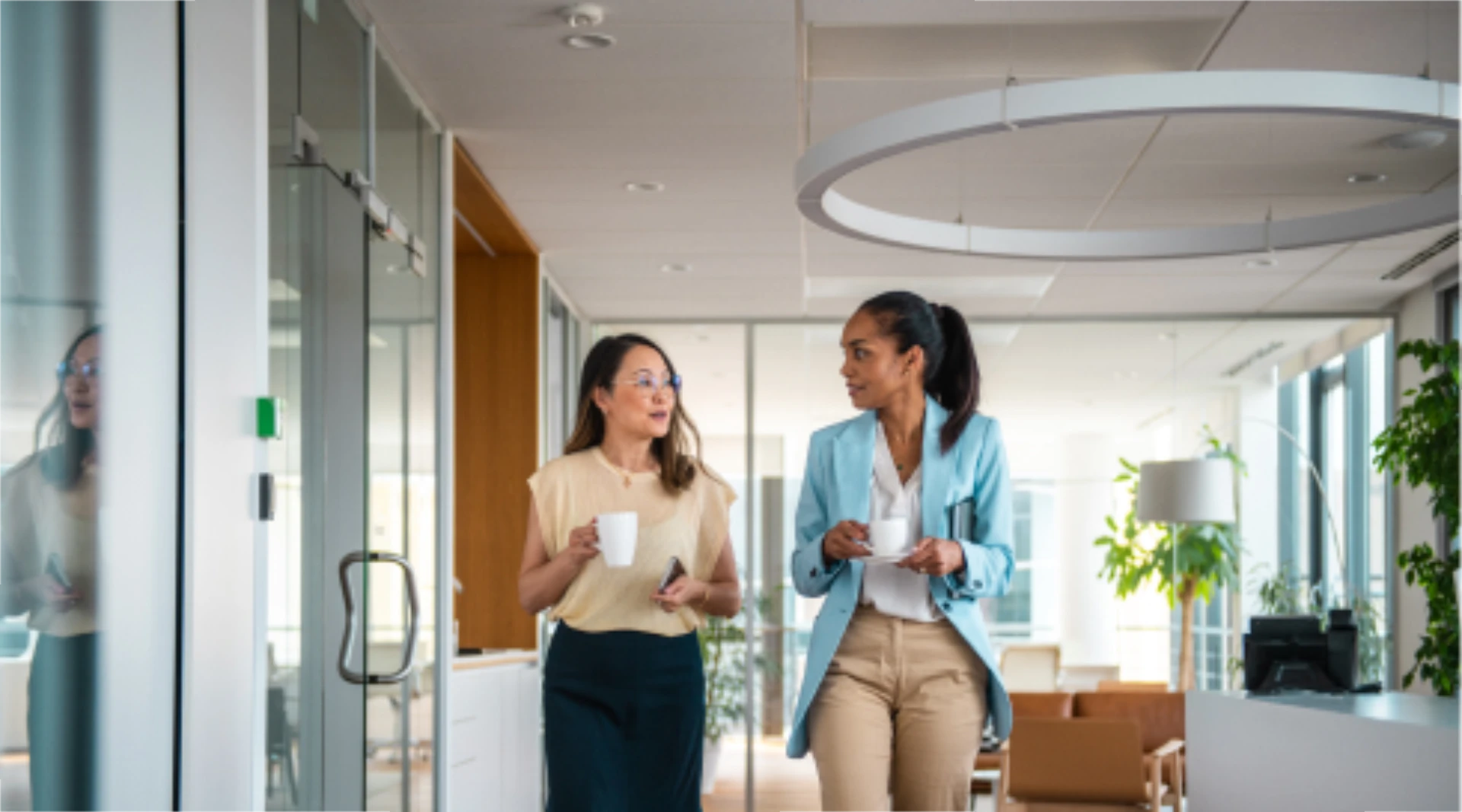 women walking through work hallway with coffee